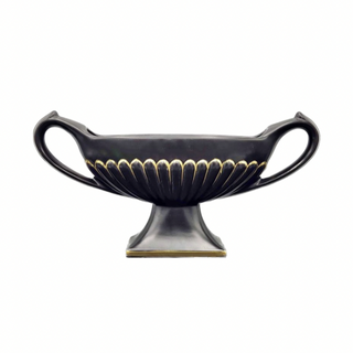 A black ceramic DEE CEE ribbed mantel vase with gold fluted detailing on a raised pedestal, designed for use on a small mantel piece or shelf.