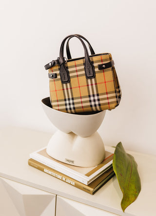 Burberry Cross Body Bag Balanced on two stacked ceramic bowls sitting on coffee table books on a sideboard