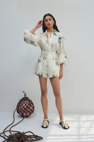 Woman in a floral outfit standing next to a textured bag on a white background
