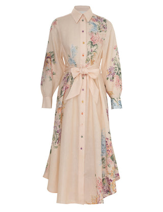 A long-sleeve button-front shirt dress in a light peach-beige color, decorated with a colorful floral print on the sleeves, sides, and hem, and finished with a matching fabric tie belt at the waist.